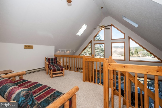 interior space featuring vaulted ceiling with skylight, ceiling fan, baseboard heating, a textured ceiling, and track lighting