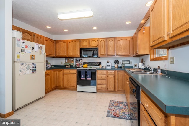 kitchen featuring dark countertops, brown cabinets, light floors, black appliances, and a sink