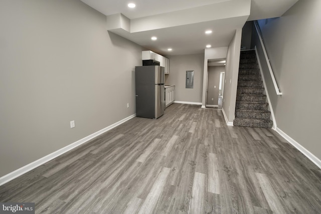 unfurnished living room with recessed lighting, baseboards, stairway, electric panel, and dark wood finished floors