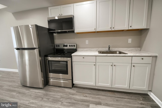 kitchen featuring appliances with stainless steel finishes, a sink, and light wood-style flooring