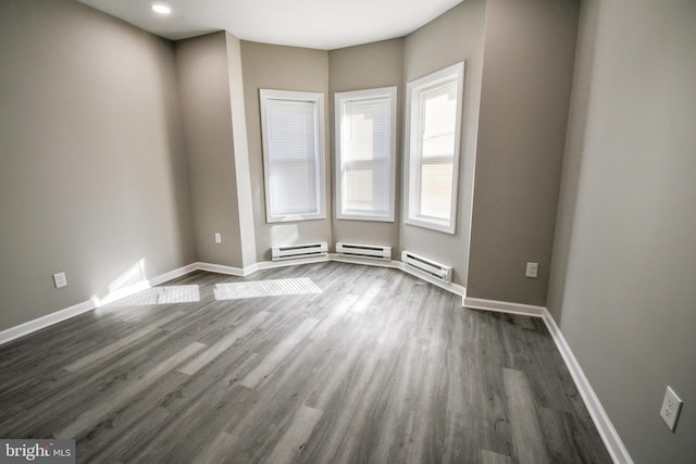 unfurnished room featuring a baseboard radiator, baseboards, and dark wood finished floors