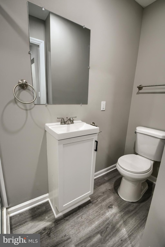 bathroom with baseboards, vanity, toilet, and wood finished floors