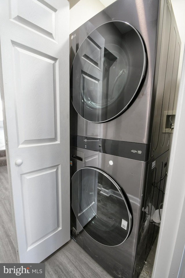 laundry room featuring laundry area, stacked washer / dryer, and wood finished floors