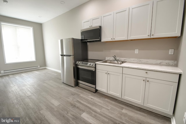 kitchen with stainless steel appliances, a sink, light wood finished floors, and baseboard heating