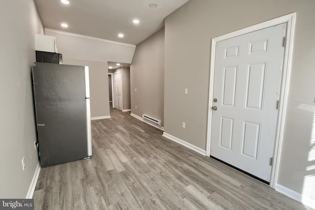 interior space featuring a baseboard radiator, light wood-style flooring, and baseboards