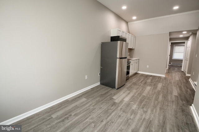 kitchen featuring a baseboard radiator, stainless steel appliances, baseboards, white cabinets, and light wood finished floors