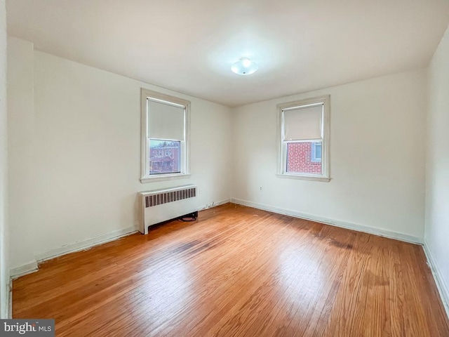 empty room with radiator, baseboards, and wood finished floors