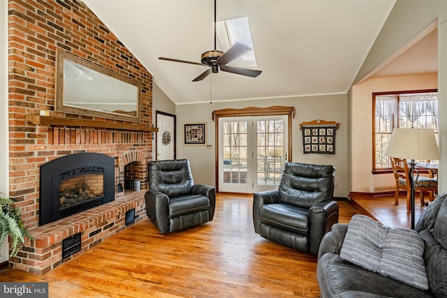 living room with lofted ceiling, a brick fireplace, wood finished floors, and a wealth of natural light