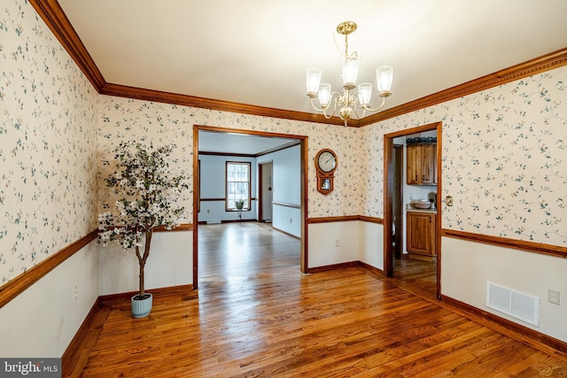 unfurnished dining area with wallpapered walls, visible vents, ornamental molding, wood finished floors, and a notable chandelier