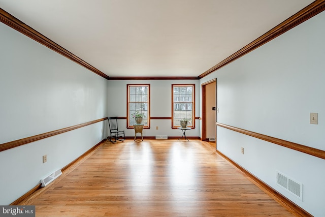 unfurnished room featuring visible vents, crown molding, light wood-style flooring, and baseboards