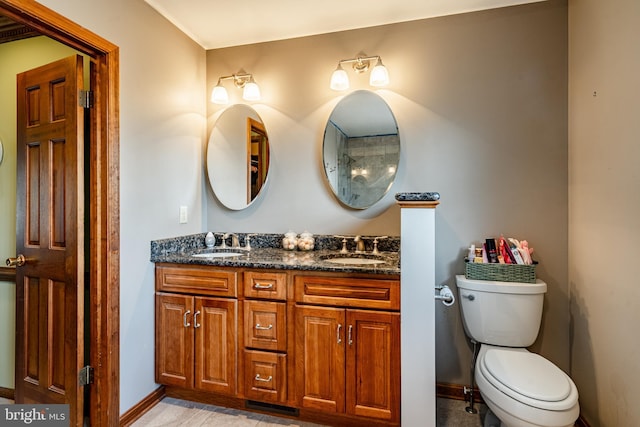 full bathroom with baseboards, a sink, toilet, and double vanity