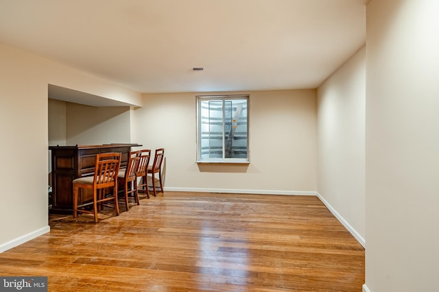 dining space with baseboards, a dry bar, and wood finished floors