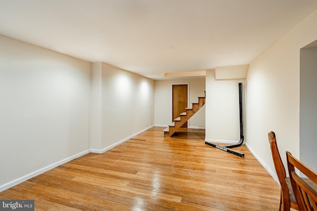 empty room featuring light wood finished floors, stairs, and baseboards