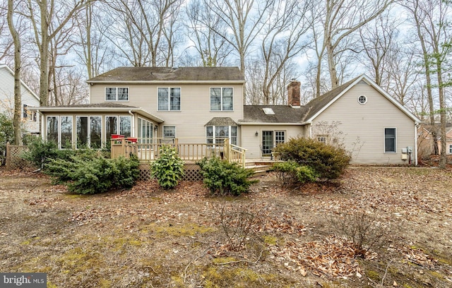 rear view of house featuring a deck, a chimney, and a sunroom