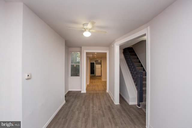 hallway with stairs, wood finished floors, and baseboards