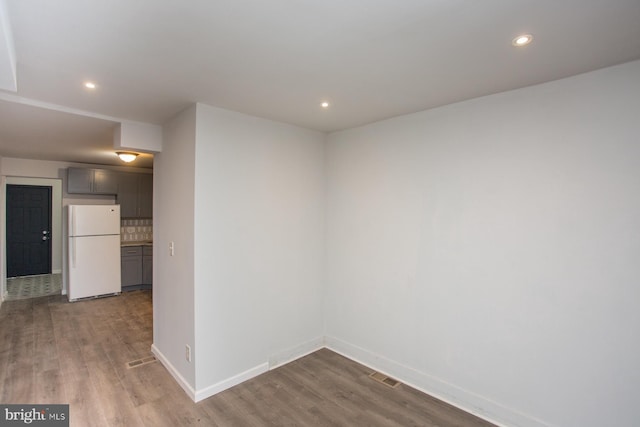 empty room with baseboards, wood finished floors, and recessed lighting