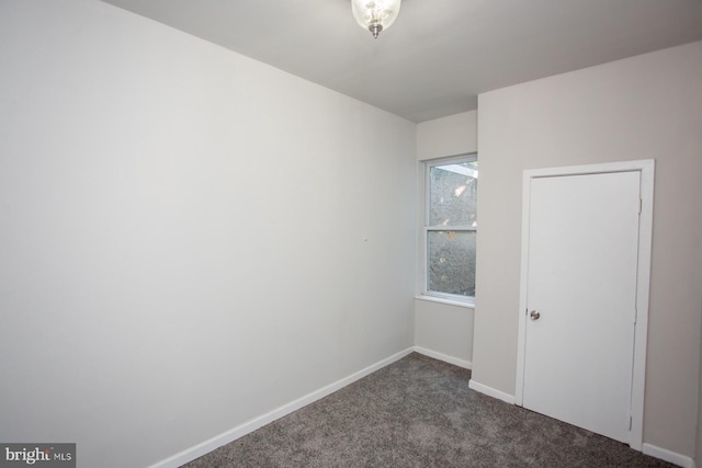 unfurnished bedroom with dark carpet and baseboards