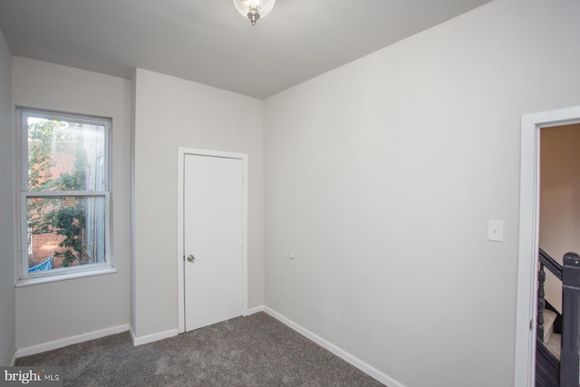 unfurnished bedroom with dark carpet and baseboards