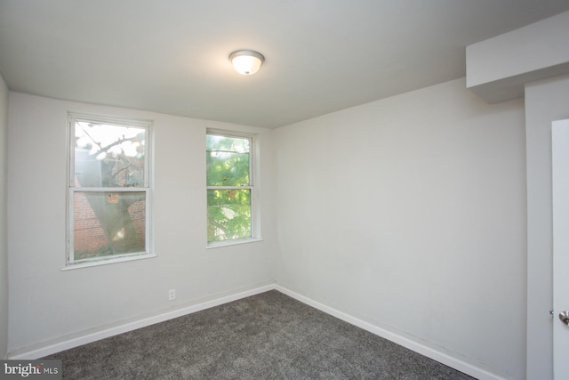 unfurnished room with dark carpet and baseboards