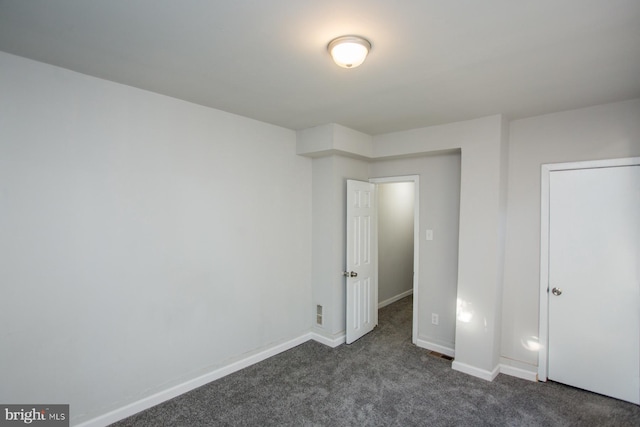 unfurnished bedroom with baseboards and dark carpet