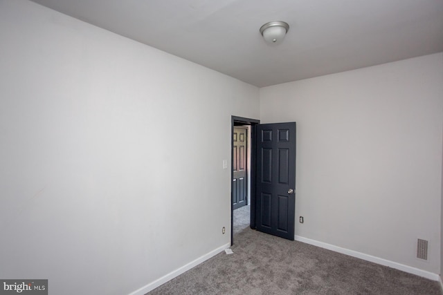 empty room featuring carpet floors, visible vents, and baseboards