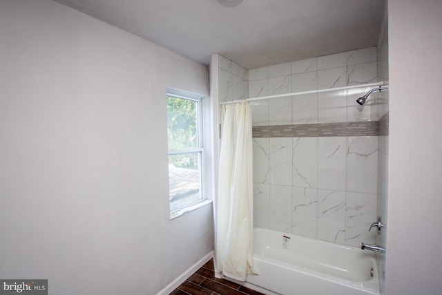 bathroom featuring wood finished floors, shower / bath combo with shower curtain, and baseboards