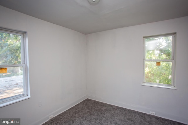 spare room featuring dark colored carpet and baseboards