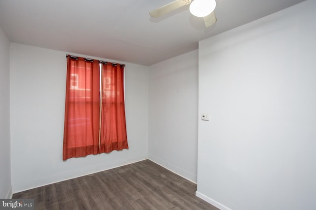 empty room with ceiling fan, dark wood-type flooring, and baseboards