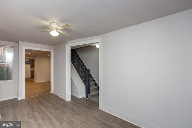 interior space with a ceiling fan, freestanding refrigerator, wood finished floors, baseboards, and stairs