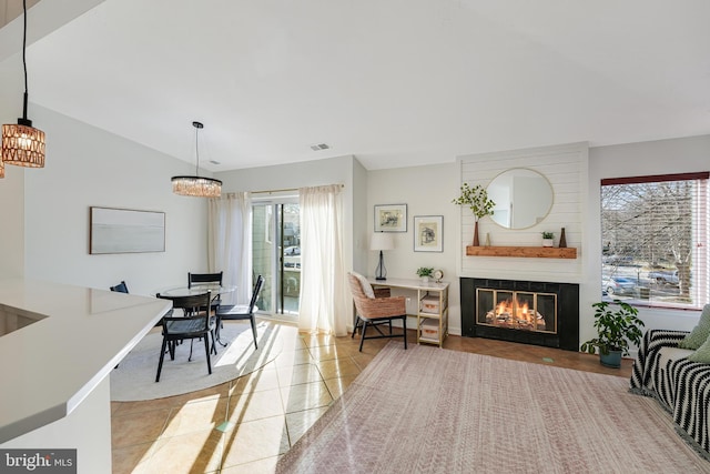 living area featuring vaulted ceiling, visible vents, a fireplace, and light tile patterned floors