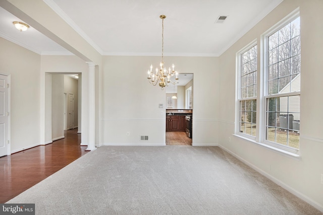 unfurnished dining area with crown molding, carpet, decorative columns, and baseboards