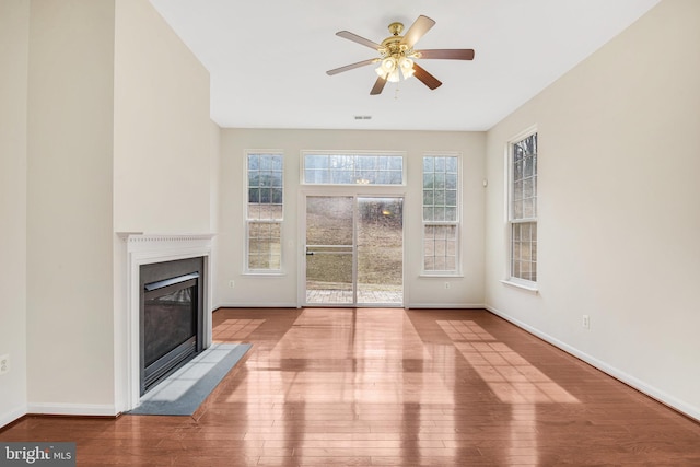 unfurnished living room with a fireplace with flush hearth, ceiling fan, baseboards, and hardwood / wood-style flooring