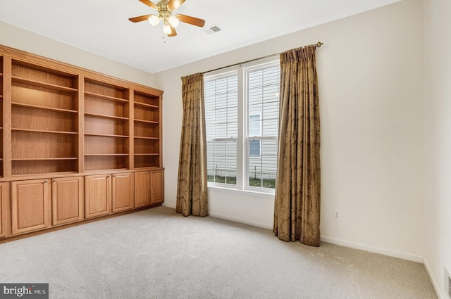 spare room featuring baseboards, visible vents, a ceiling fan, and light colored carpet