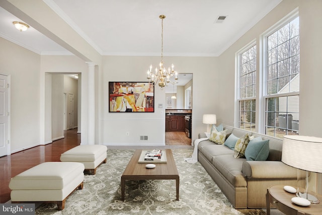 living area featuring visible vents, wood finished floors, decorative columns, and crown molding