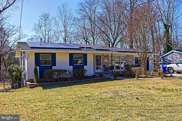 ranch-style house with roof mounted solar panels and a front lawn