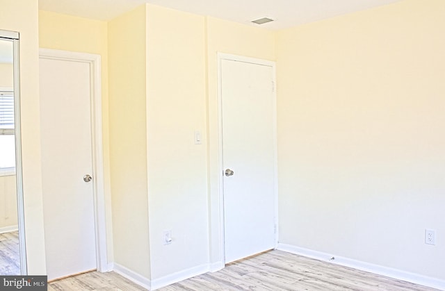 unfurnished bedroom with light wood-style flooring, visible vents, and baseboards