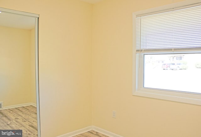 empty room with visible vents, light wood-style flooring, and baseboards