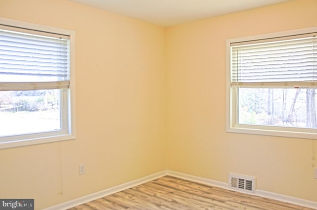 unfurnished room featuring baseboards, visible vents, and light wood-style floors