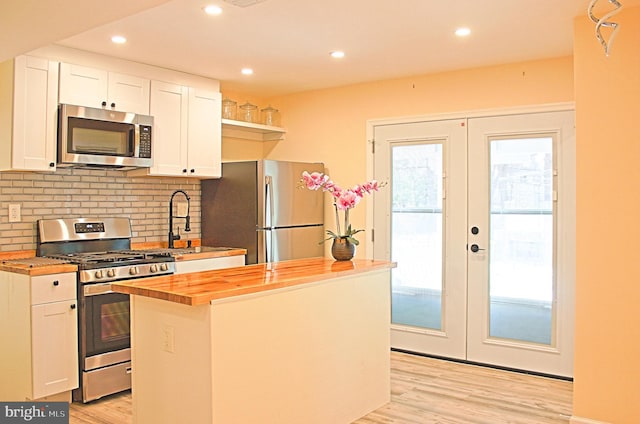 kitchen featuring stainless steel appliances, white cabinets, wooden counters, french doors, and light wood-type flooring