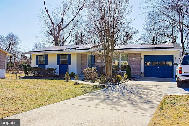 ranch-style home featuring an attached garage, solar panels, brick siding, concrete driveway, and a front lawn