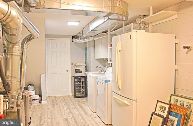 clothes washing area featuring laundry area, washer and clothes dryer, light wood-type flooring, and concrete block wall