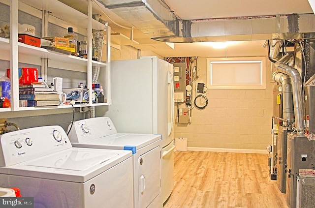 washroom with laundry area, independent washer and dryer, light wood-style flooring, and concrete block wall