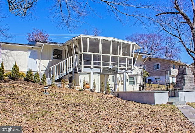 rear view of house featuring stairway and a sunroom