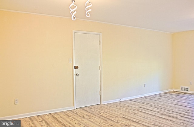 spare room featuring baseboards, visible vents, wood finished floors, and ornamental molding