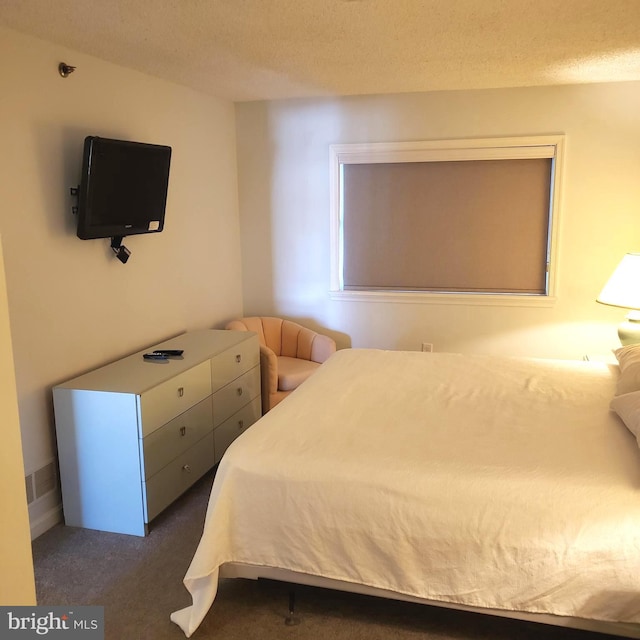 bedroom featuring dark colored carpet and a textured ceiling