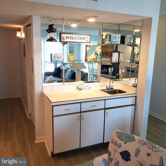 kitchen featuring white cabinets, dark wood-style flooring, a sink, and light countertops