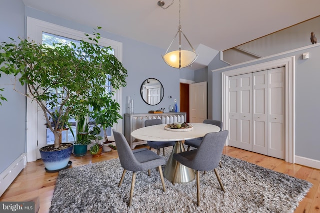 dining room with baseboard heating, light wood-style flooring, and baseboards