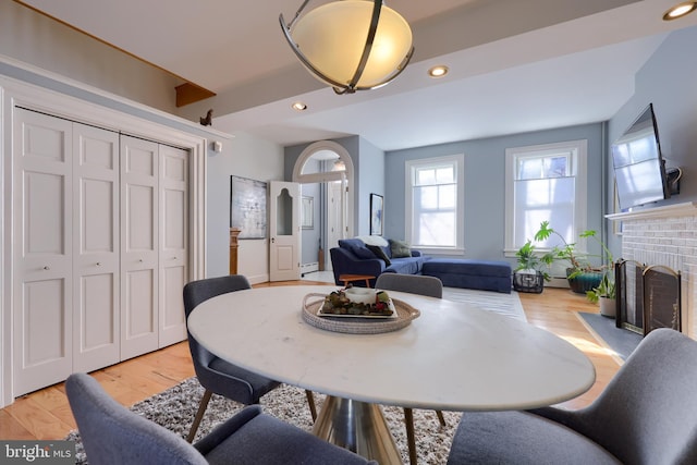 dining room featuring a brick fireplace, recessed lighting, light wood-type flooring, and baseboard heating