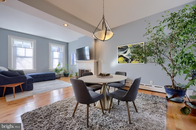 dining area with recessed lighting, a fireplace, a baseboard heating unit, and wood finished floors