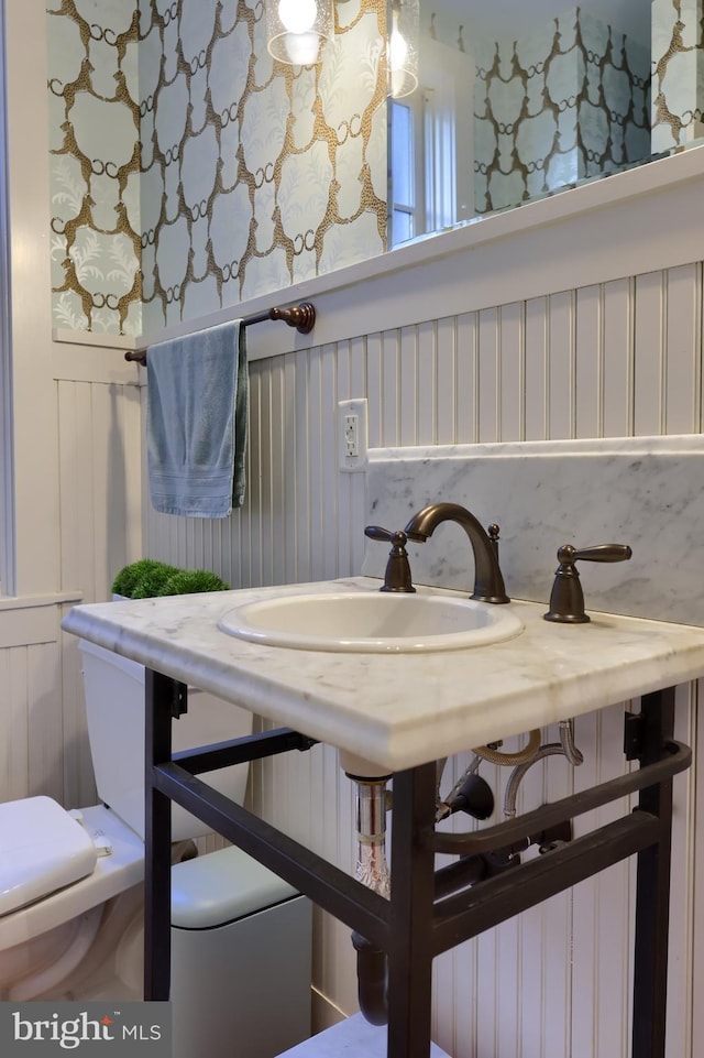 half bath featuring wainscoting and toilet